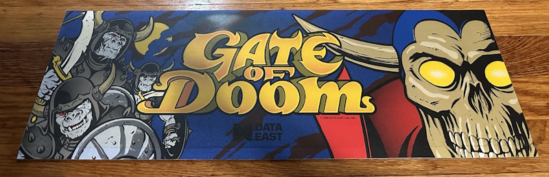 GATE OF DOOM marquee, featuring a smiling skull man and some orcs