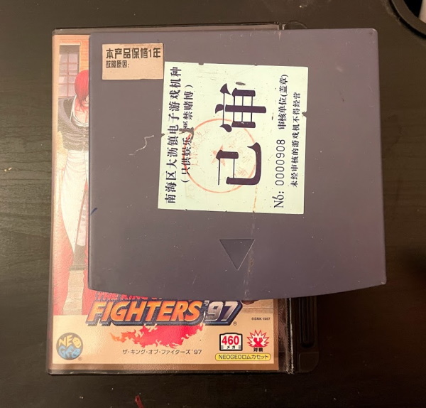 A blue box, the circuitboard in question, on top of a copy of King of Fighters '97 for the AES for scale
