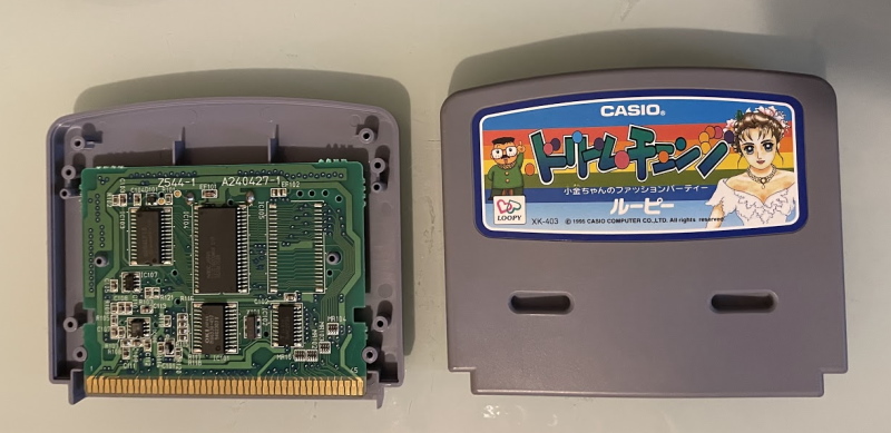 A circuitboard next to a Casio Loopy cartridge exterior