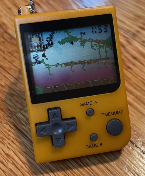 A small Game Boy-shaped device with an LCD screen showing a level of Donkey Kong Jr