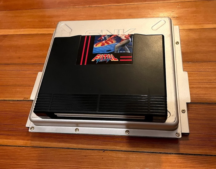 Fatal Fury for the AES sitting on top of a Hyper Neo Geo 64 cartridge, an imposing grey metal box.