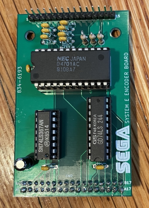 A small circuit board with a large IC and some pins