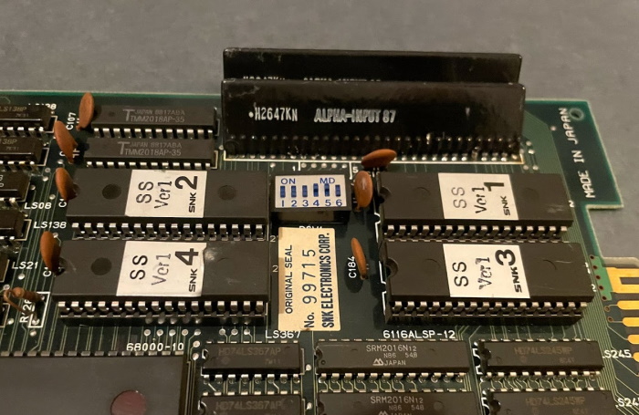 Circuitboard of Sky Soldiers. Two larege black chips, connected only at one side, are labeled ALPHA INPUT-87