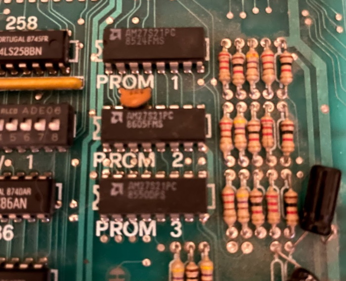 Paddle Mania circuitboard, closeup on several chips labeled PROM1, PROM2, and PROM3. Two capacitors in the bottom right