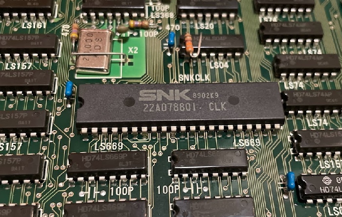 A chip labeled SNK 22A078801 CLK, next to a timing crystal