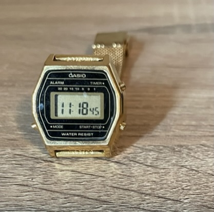 A gold-colored Casio digital watch with an LCD display