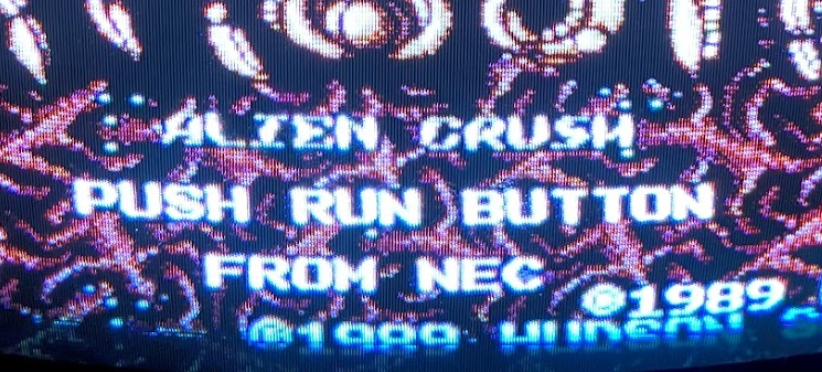 A cropped segment of the Alien Crush titlescreen running on Turbo Duo. It is a photo of a CRT television