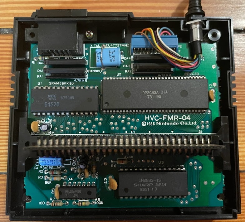 The Famicom Disk System RAM adapter inside, showing the chips, most notably the 2C33