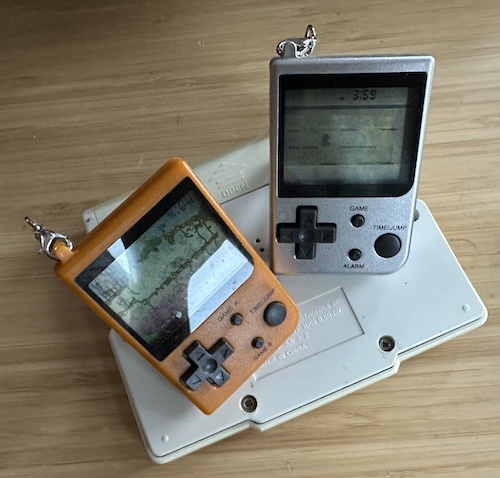 THEN PERISH Two Game and Watch games repackaged into cheaper Game Boy-shaped shells sitting on top of the Tiger Miniature Golf, which is upside down.