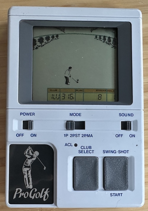 all the pleasures of real golf Grey plastic with an LCD screen, showing a golfer. There are only buttons for club select and swing