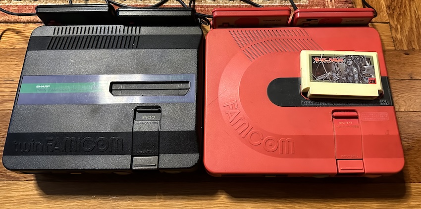 Two twin Famicoms, a newer green model and an older red model