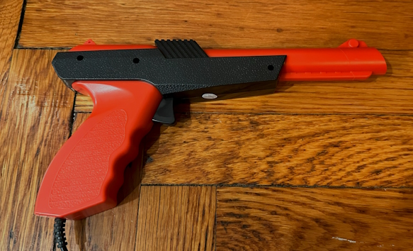 A Tomee light gun. It has no visible branding, and is made of orange and black plastic