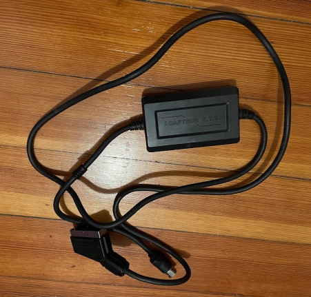 A scart cable lying on a hardwood floor. There is a box in the middle