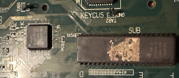 Photo of a surface-mount chip next to a socketed ROM