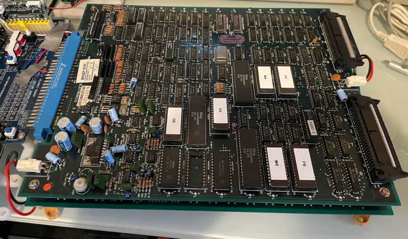 Athena circuitboard plugged into a supergun. The Athena board is two layers. The supergun is blue and covered in soldered wires and duct tape