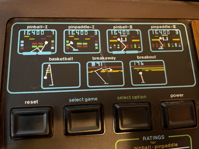 A close up on the device. It shows the seven included games, with small diagrams of each.