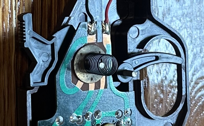 Zoomed in to show a punched metal disk and the cocking mechanism
