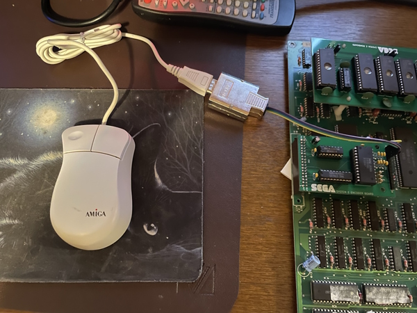An Amiga-branded mouse sitting on the desk now attached to the circuitboard