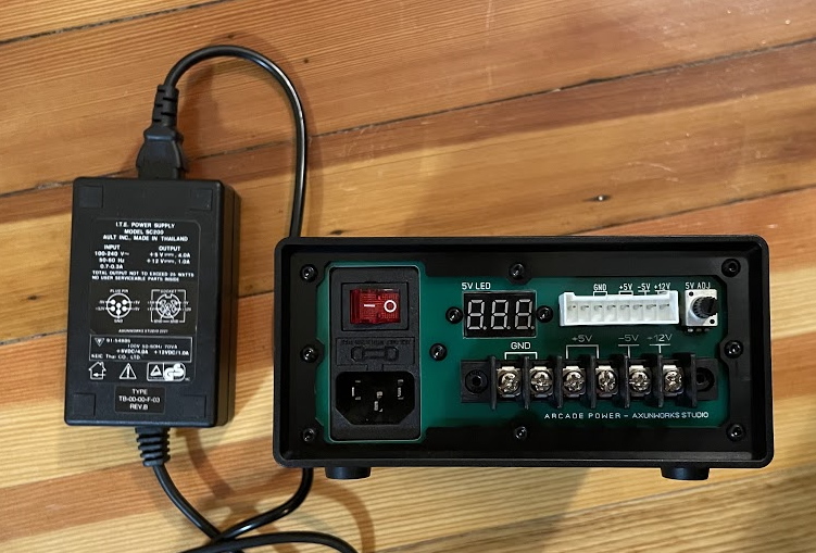 A power brick next to a larger arcade power supply